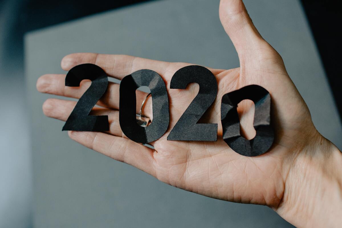 Número 2020 feito de papel preto na mão de uma pessoa