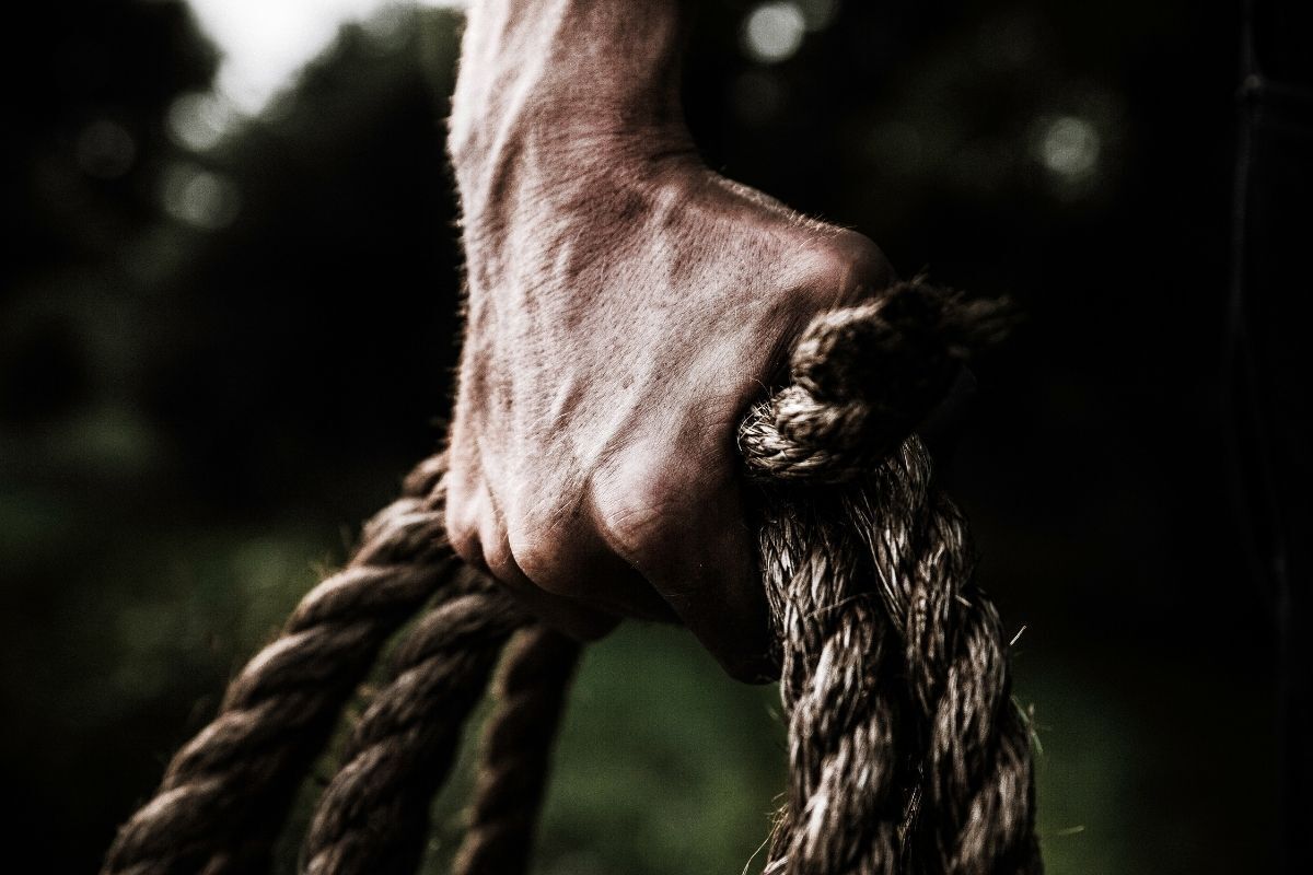 Homem segurando cordas com força.