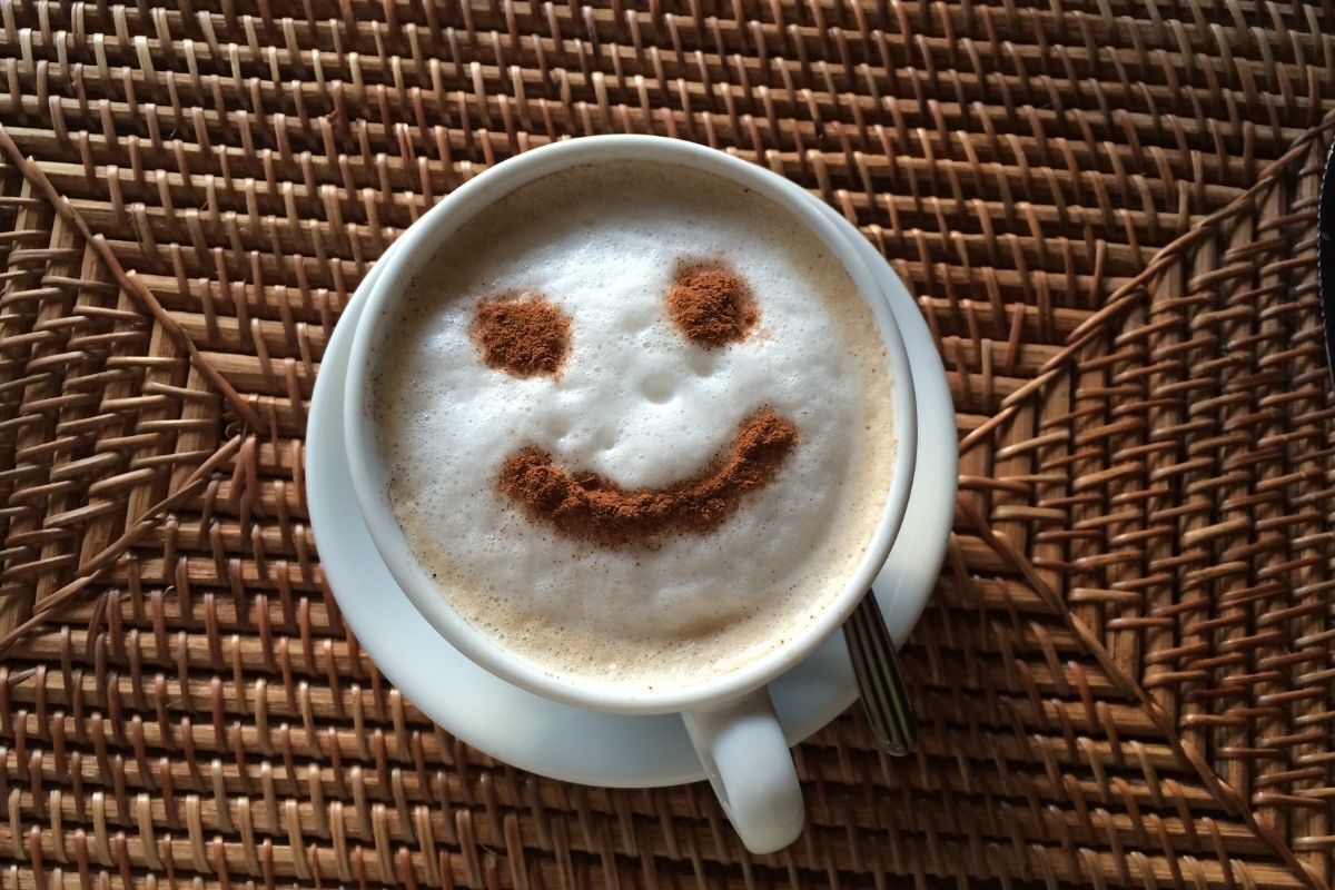 Xícara de café com rosto feliz desenhado.