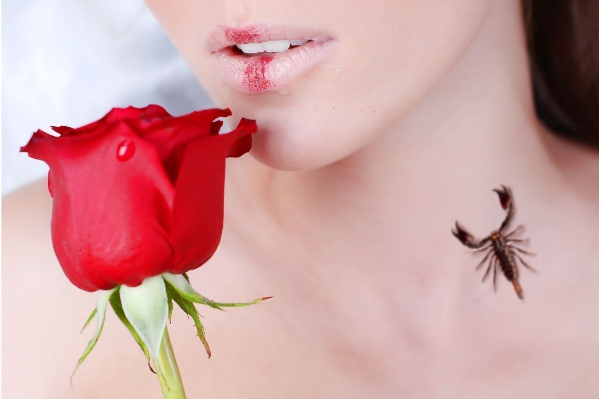 Mulher beijando uma rosa. A tatuagem de um escorpião é visível em seu pescoço.