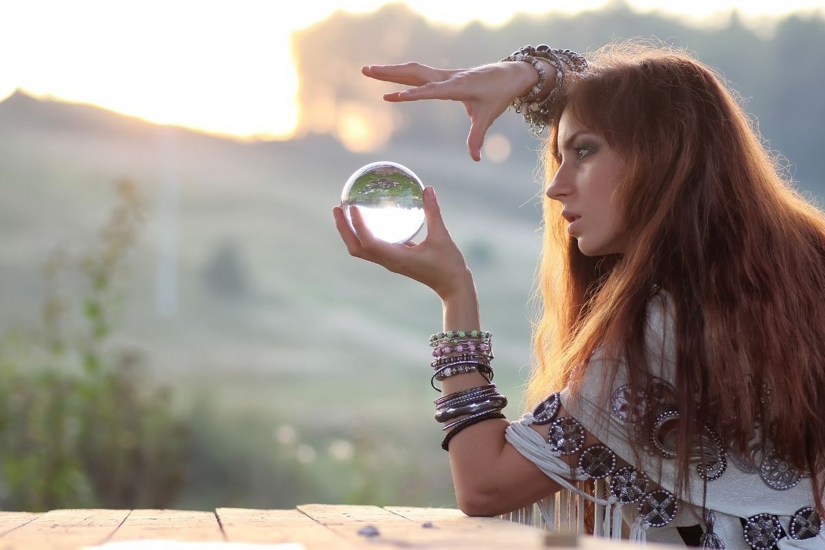 Bruxa com uma bola de cristal em suas mãos, admirando o futuro