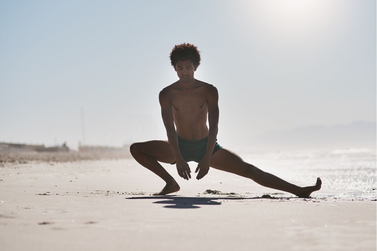 Homem praticando Yoga na praia, a imagem representa o equílibrio na vida.