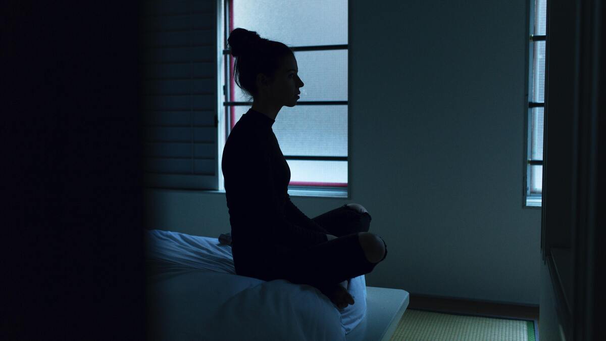 Mulher meditando na cama. 