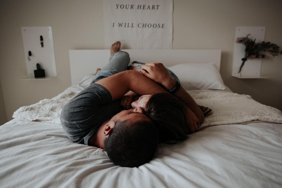Casal se beijando na cama.