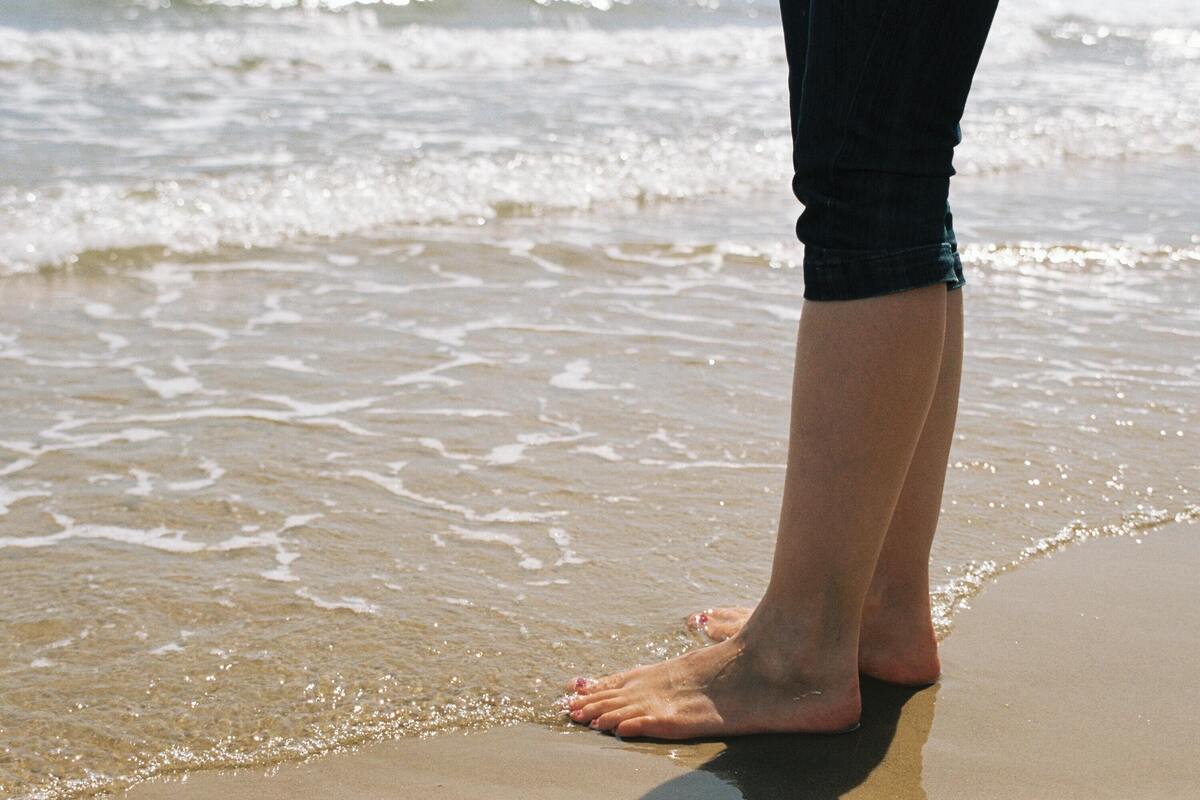 Homem descalço na água da praia