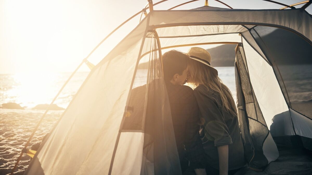 Casal se beijando dentro de uma barraca.