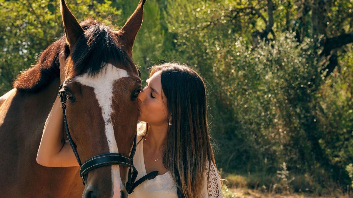Mulher beijando um cavalo manso.