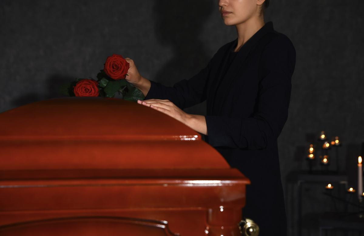 Mulher colocando rosas em caixão