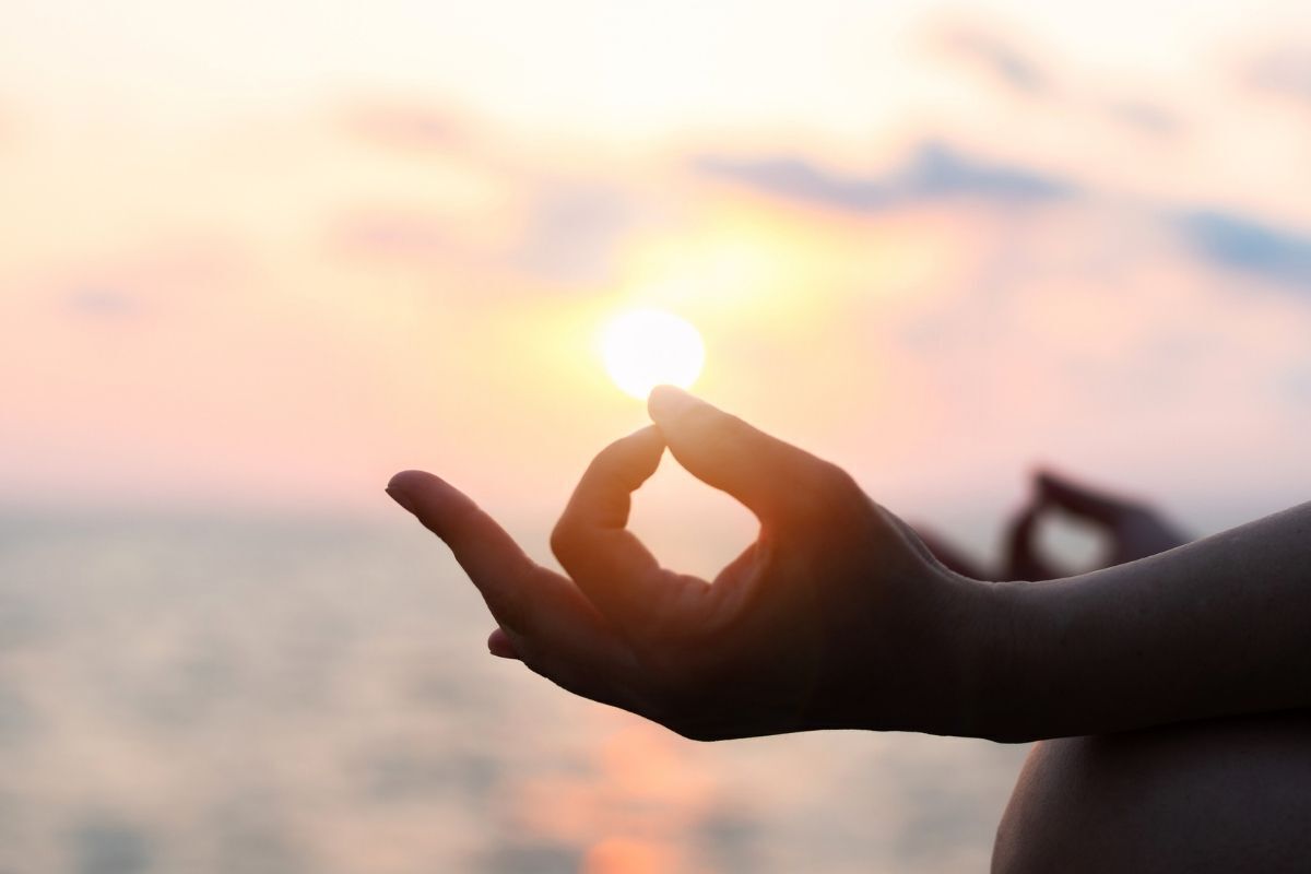 Prática de meditação, silhueta de uma mulher meditando na praia ao pôr do Sol