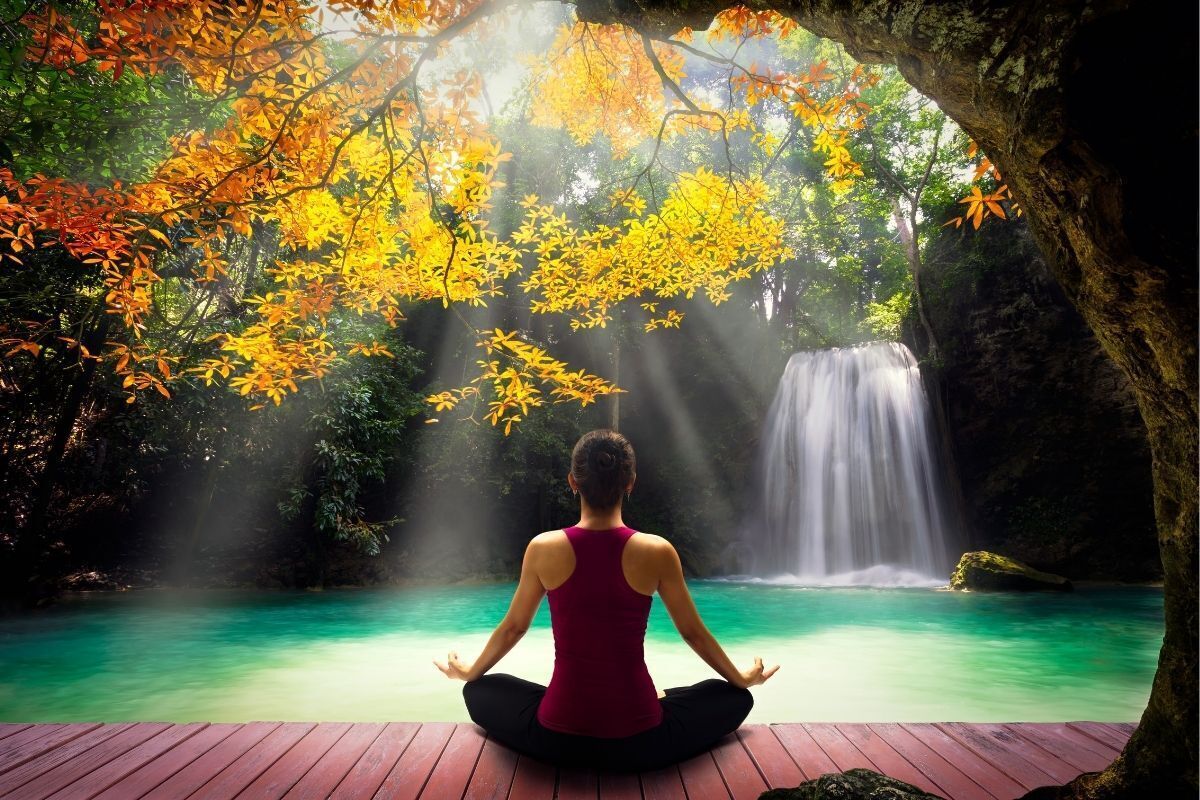 Mulher meditando em uma linda cachoeira com água cristalina e flores amarelas
