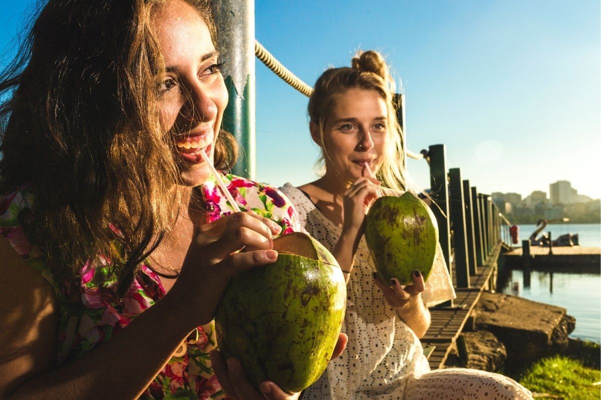Mulheres sorrindo e bebendo água de coco natural