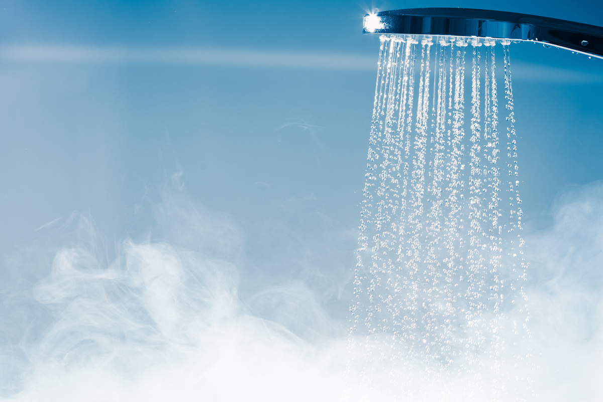 Chuveiro despejando água, enquanto vapor surge pelo ambiente, simbolizando tomar banho de água quente.
