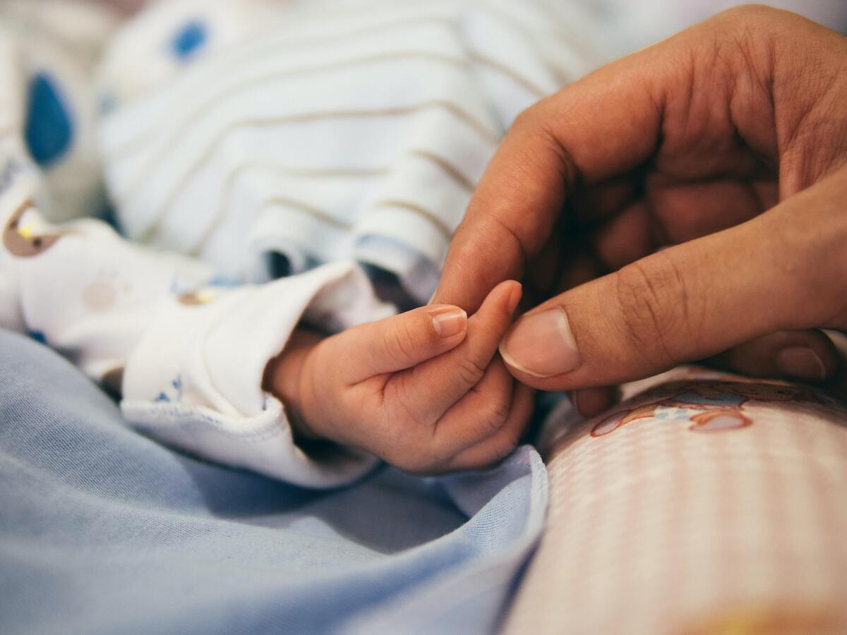 Mãe segurando mão de um bebê recém nascido. 