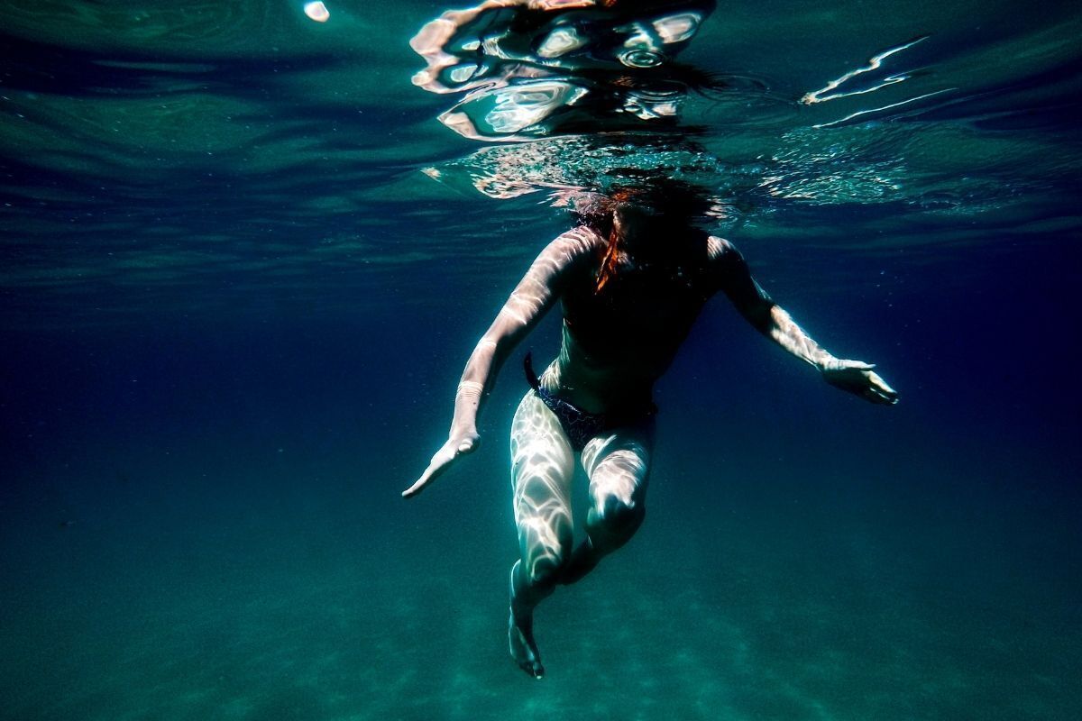 Homem mergulhando em águas profundas e escuras