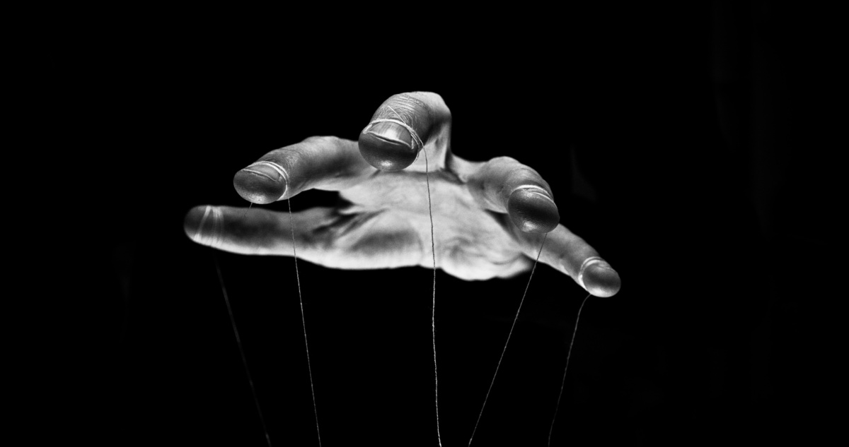 Mão com fios de marionete simbolizando o desejo por controle