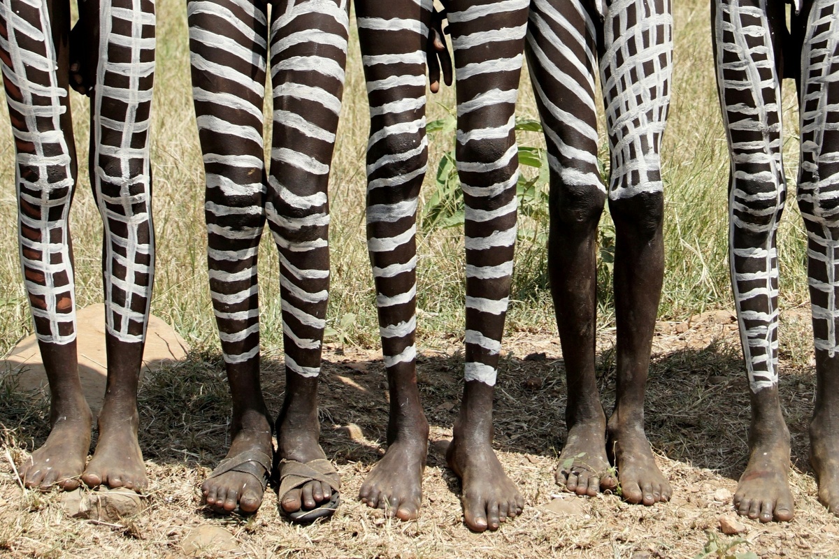 Pessoas com pernas pintadas de branco em ritual africano