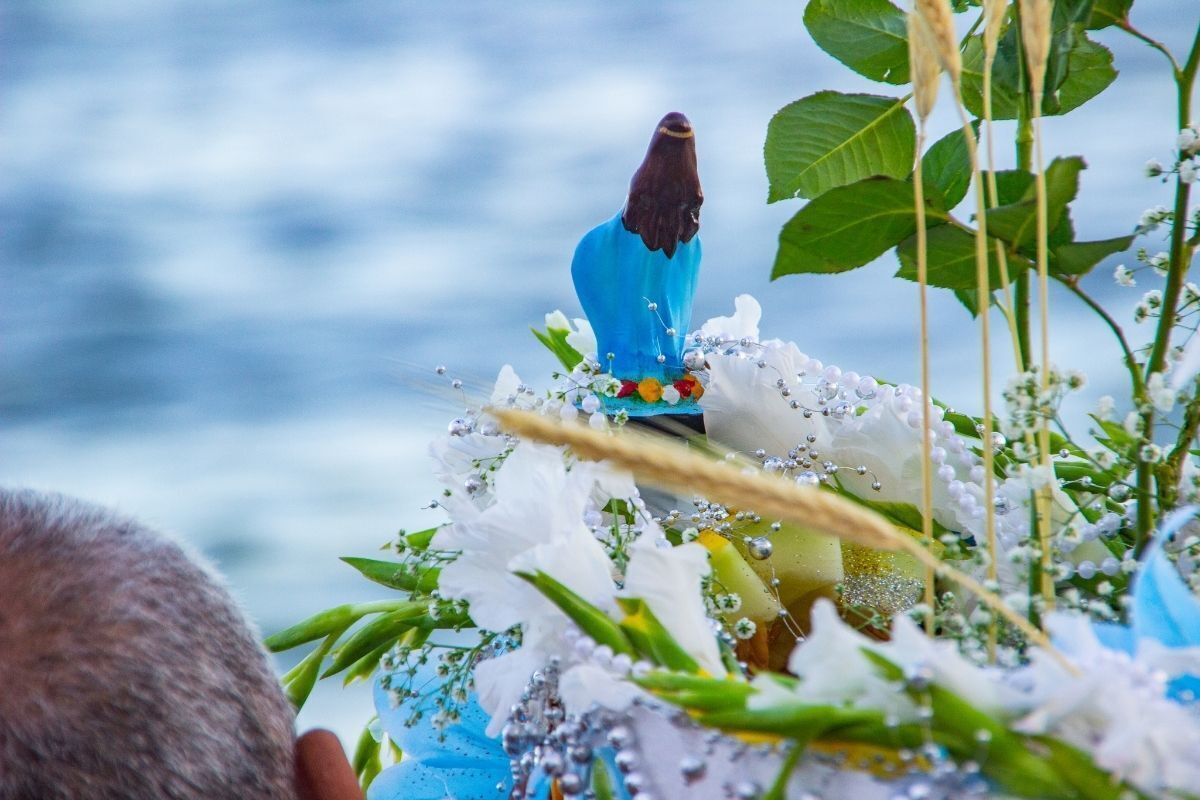 Imagem de Iemanjá com flores nas pedras do mar