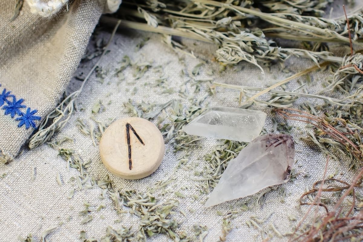 Runa Laguz Runa de madeira em um pano de linho áspero com cristal de ametista, cristal de rocha e absinto seco