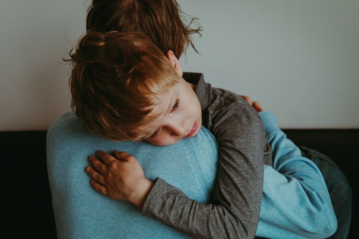 Criança triste abraçando a sua mãe