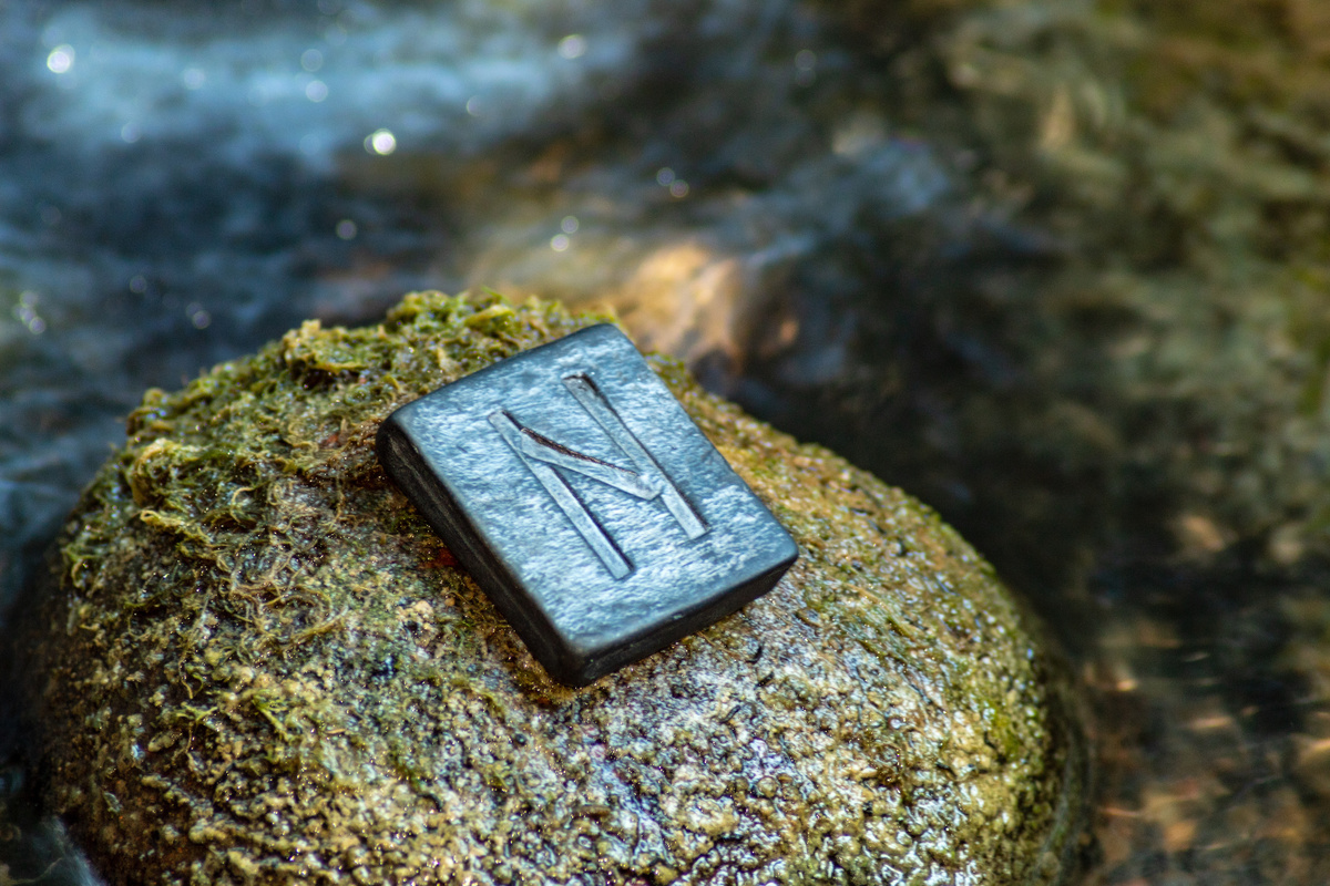Pedra com a runa Hagalaz sob uma rocha