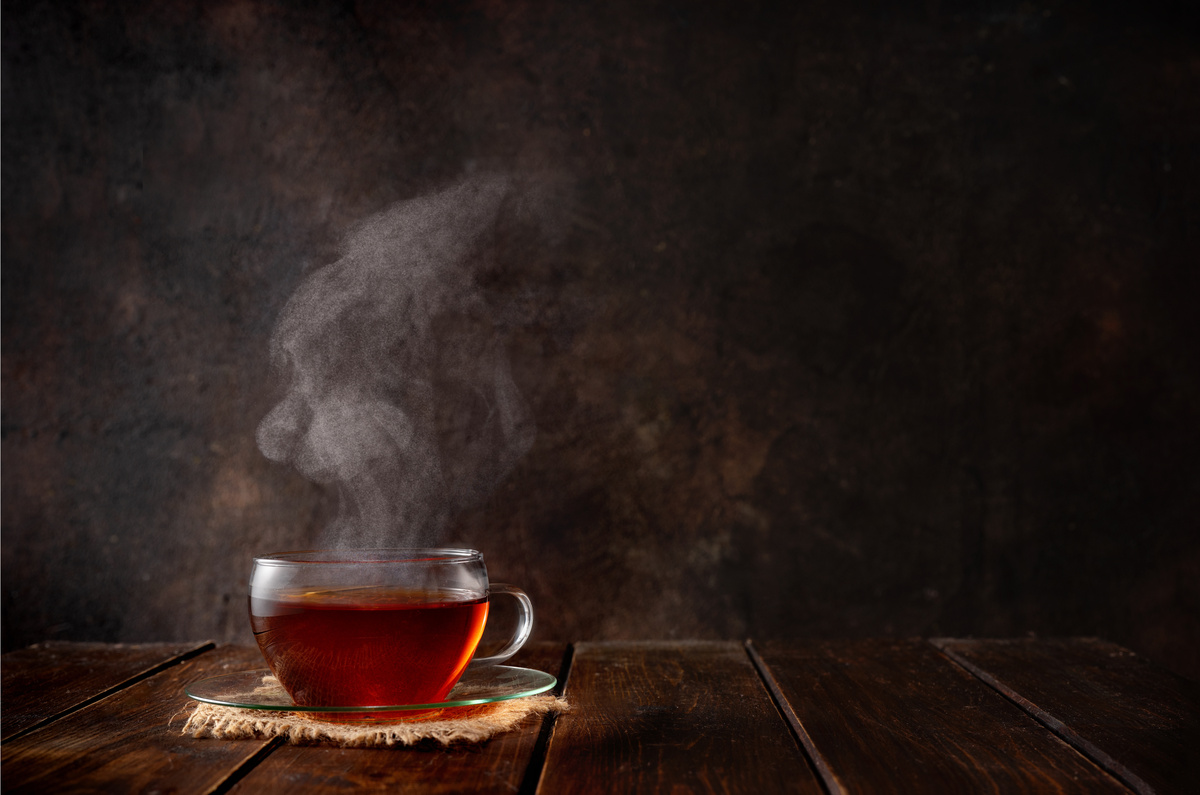 Xícara de chá sobre superfície de madeira em fundo escuro