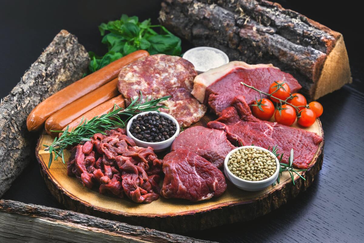 Vários tipos de carne em uma bandeja de madeira. 