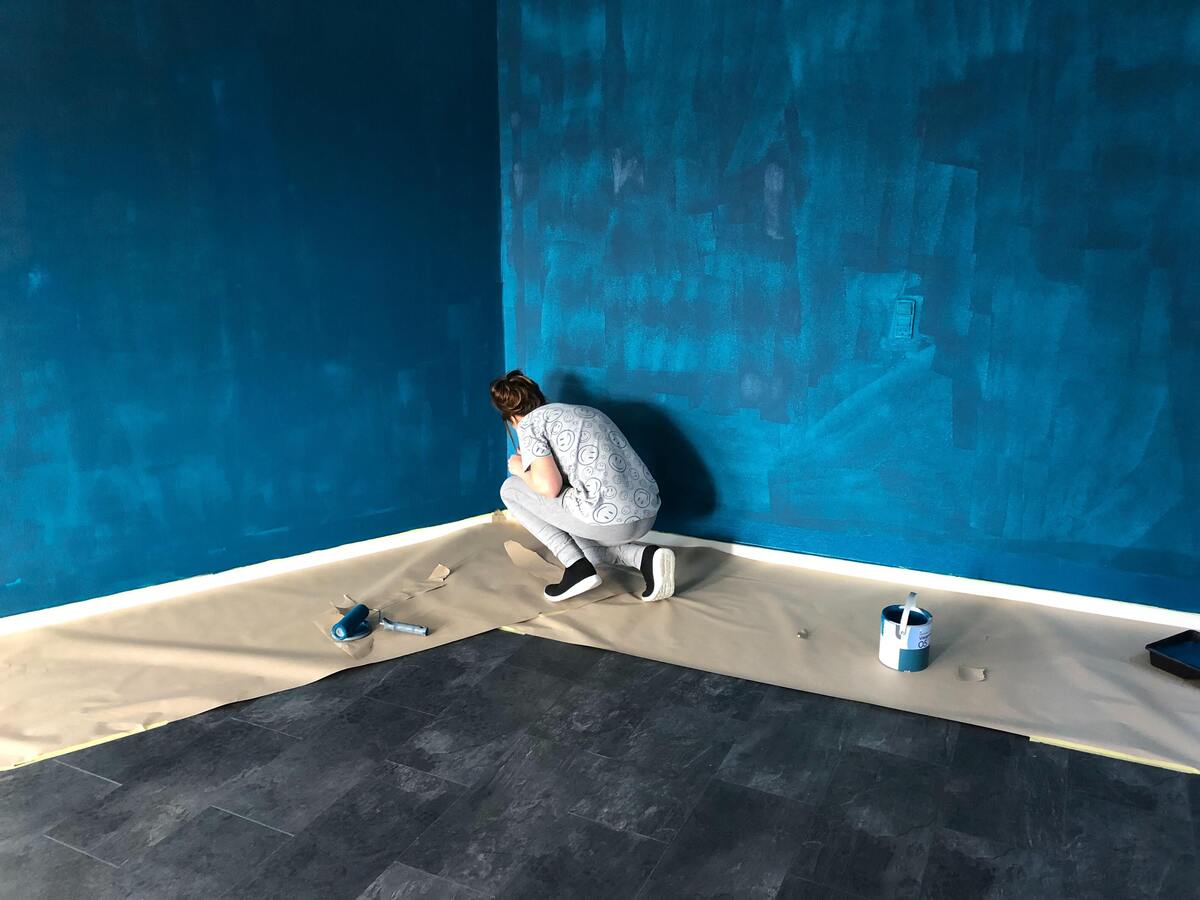 Pessoa pintando uma parede de azul. 
