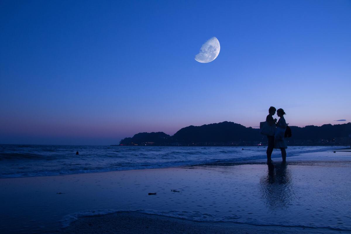 Casal se beijando em uma praia durante a noite.
