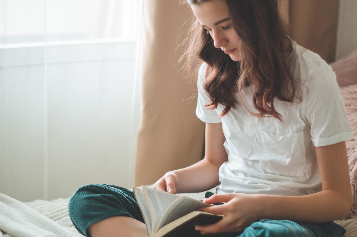 Adolescente lendo Bíblia sentada na cama