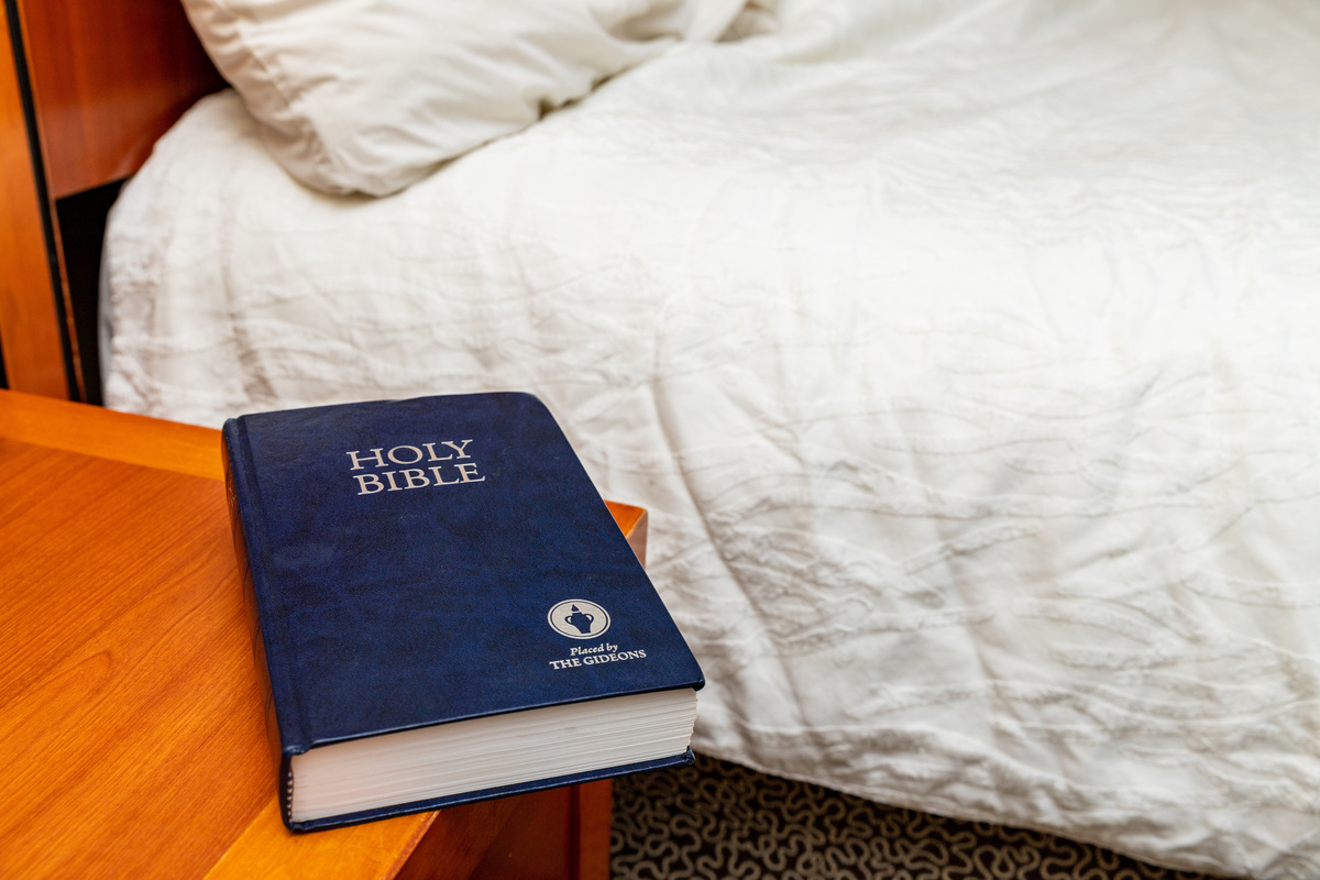 Bíblia em criado mudo ao lado de uma cama