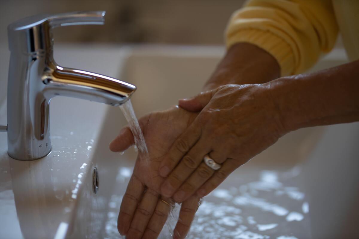Pessoa lavando a mão em torneira