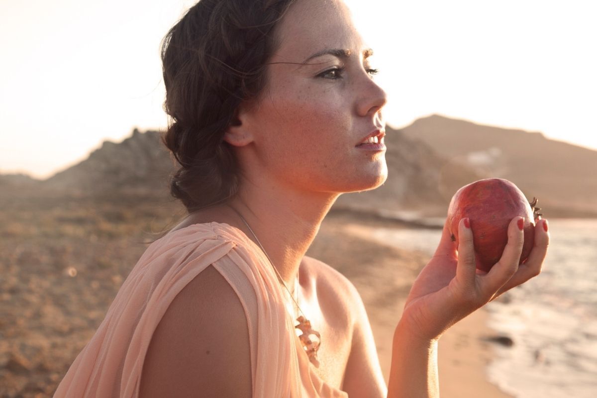Mulher caracterizada como Perséfone com uma maçã nas mãos