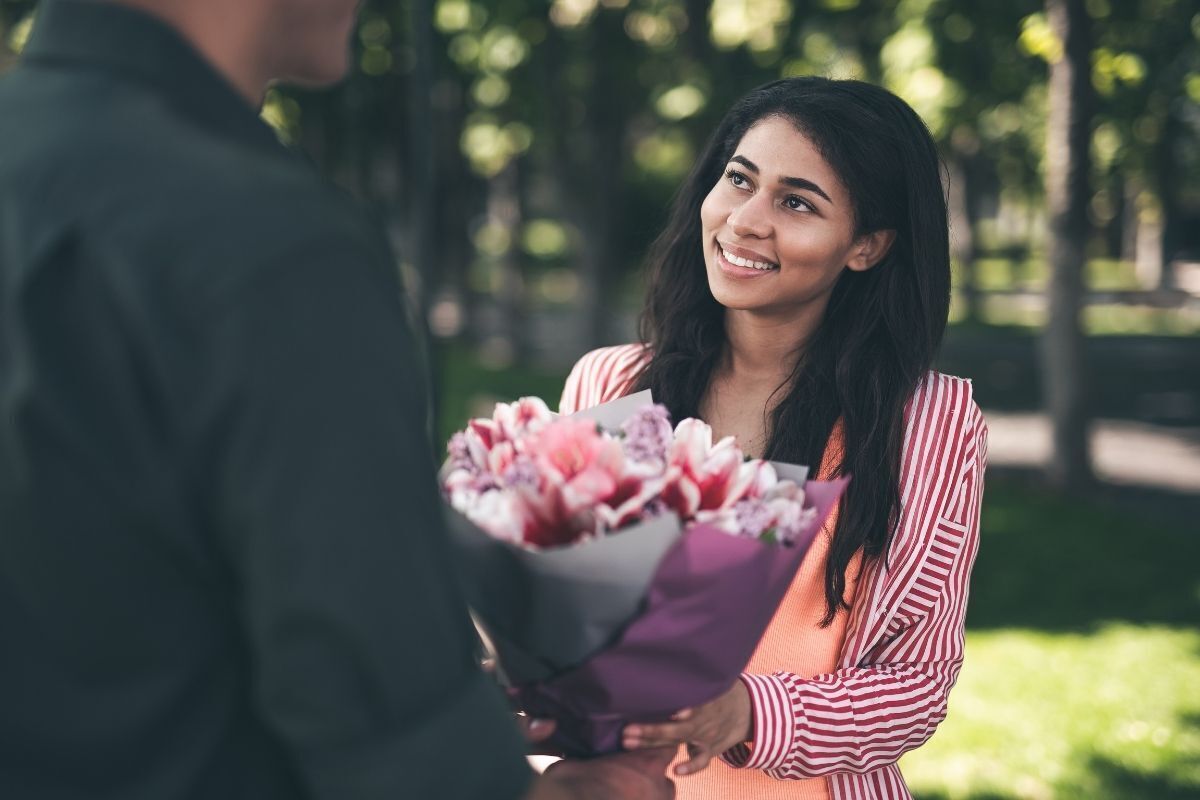 Mulher sorrindo ao receber um buquê de flores
