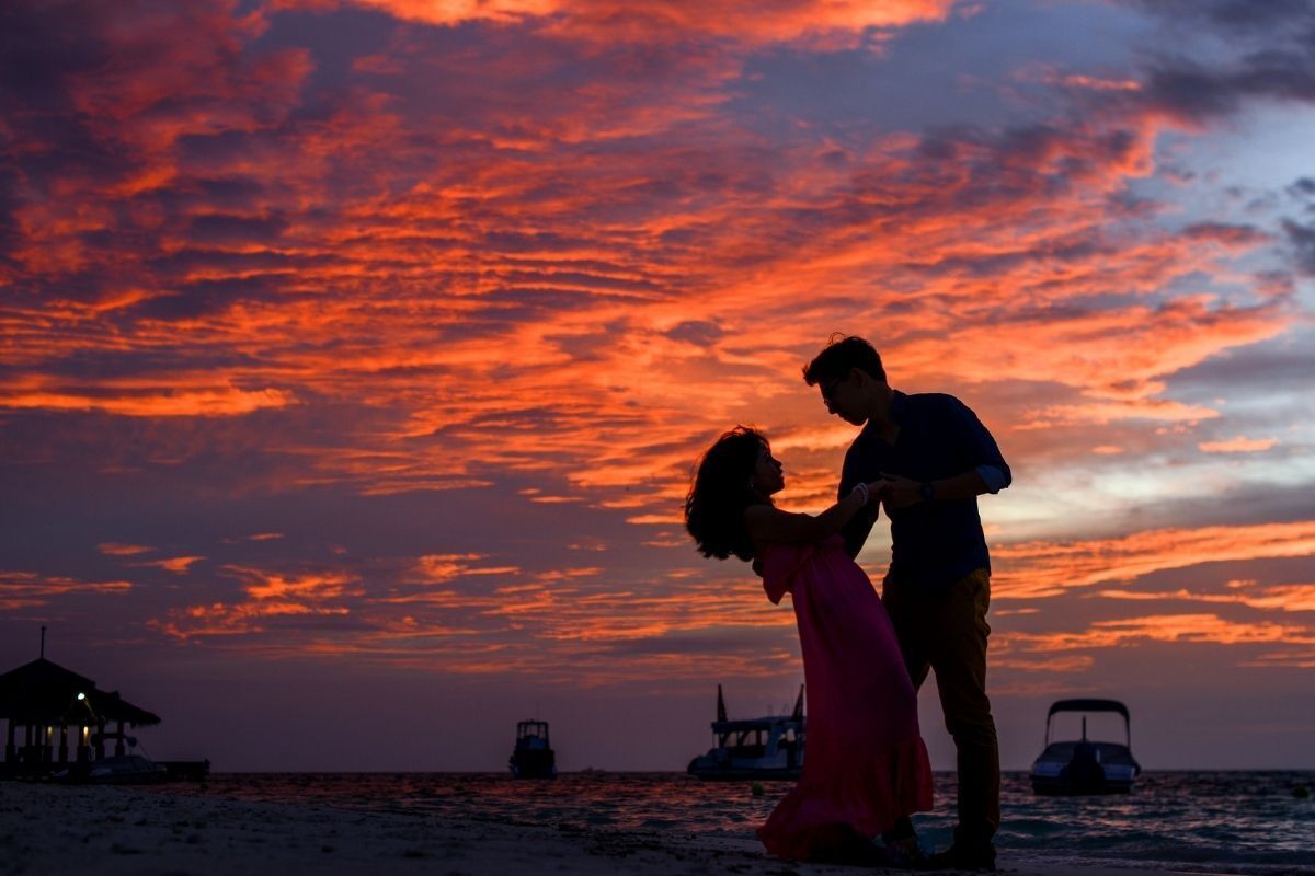 Silhueta de um casal dançando na praia ao pôr do sol