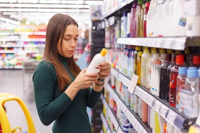 Mulher no supermercado escolhendo shampoo anticaspa