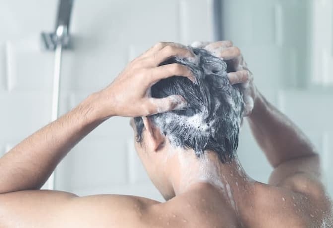 Homem lavando o cabelo com shampoo anticaspa