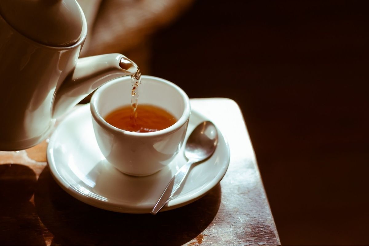 Chá de boldo sendo servido em uma xícara branca