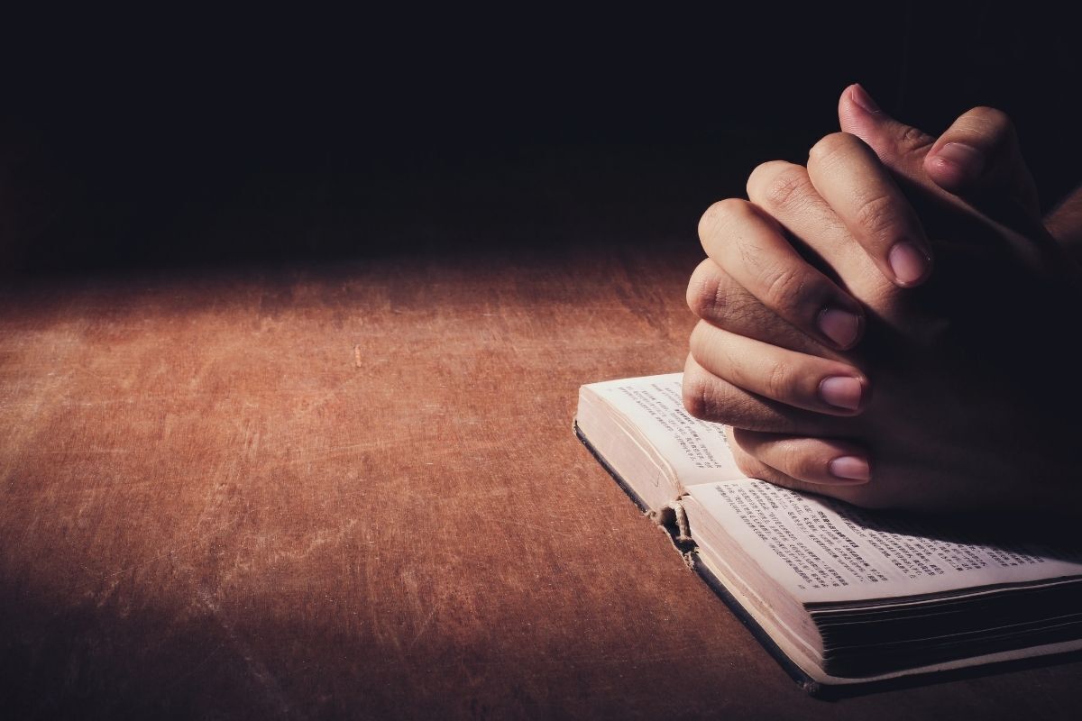 Pessoa fazendo uma oração sob a Bíblia