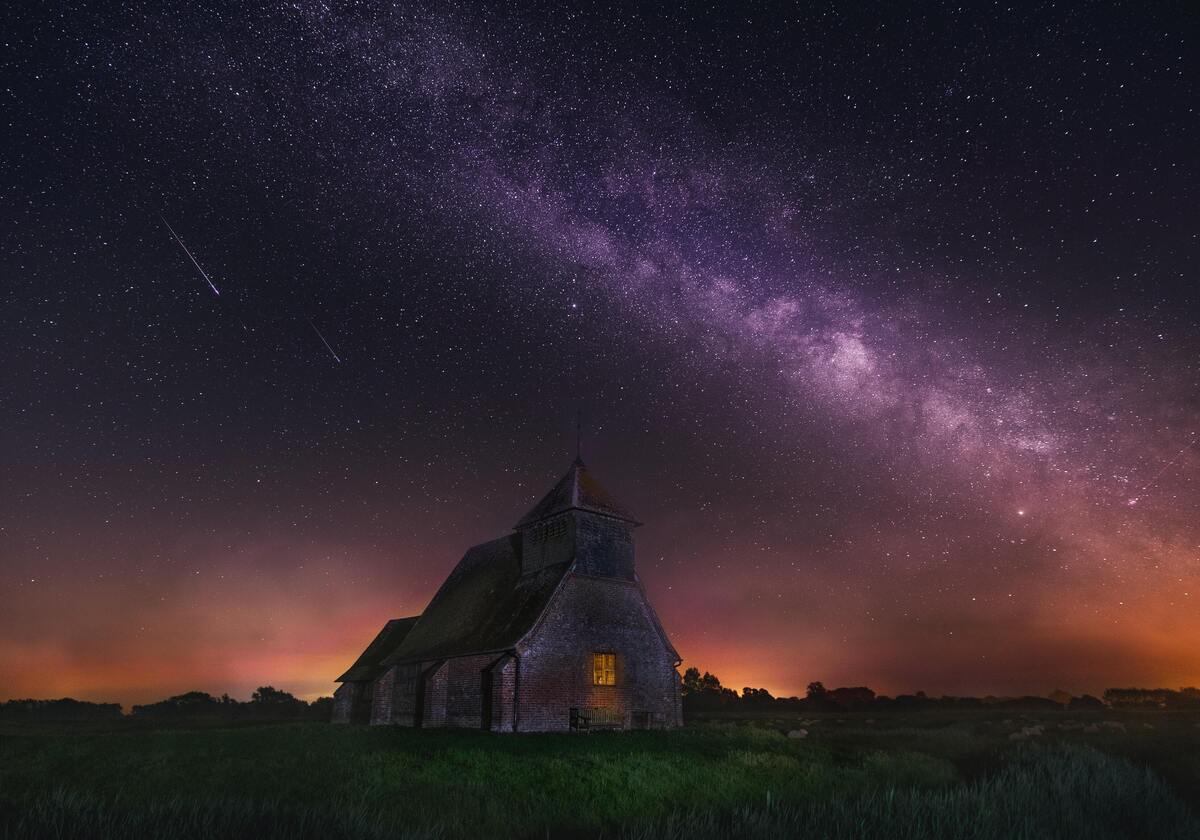 Meteoro em céu estrelado e uma casa. 