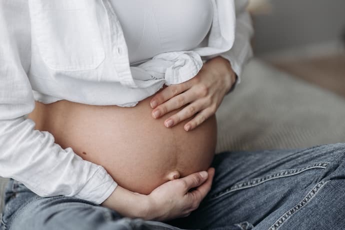 Mulher grávida sentada segurando a barriga