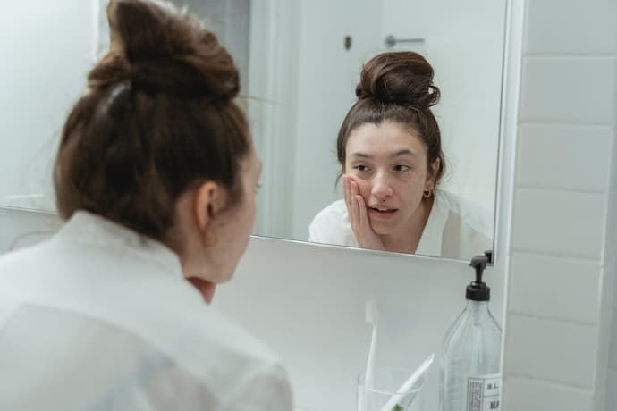 Mulher olhando rosto no espelho