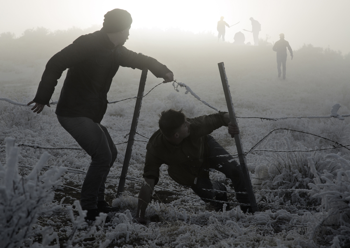 Homens fugindo passando por cerca em uma guerra