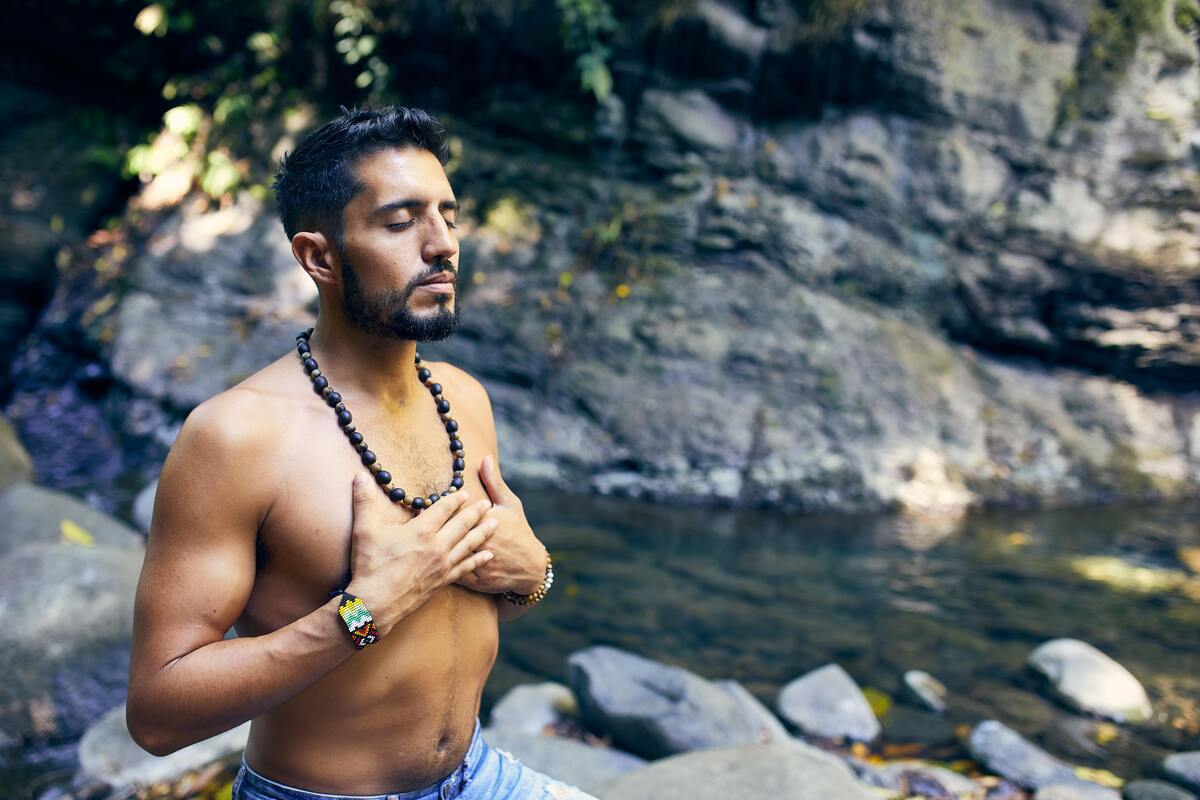 Homem meditando com as mãos no peito. 