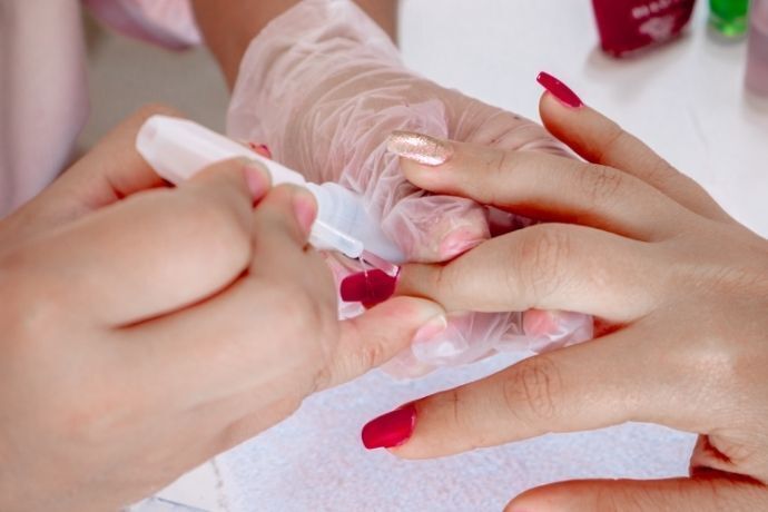Pessoa na manicure pintando as unhas com esmalte em gel