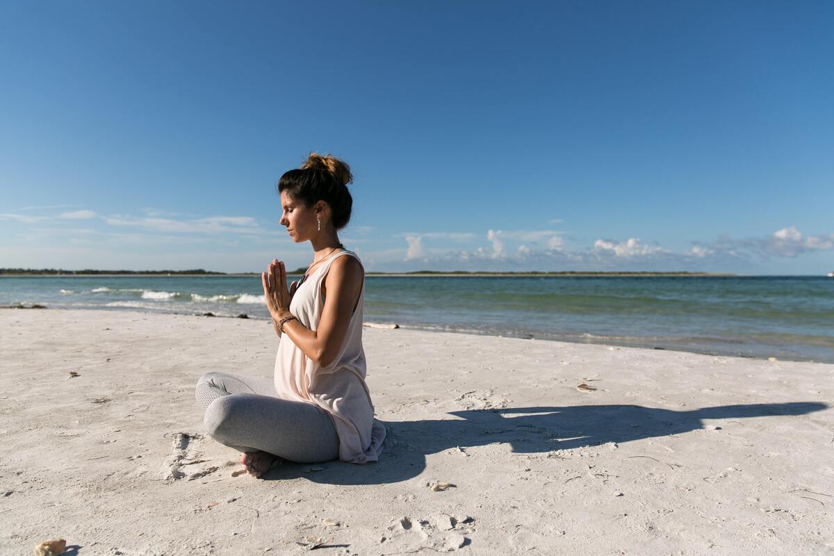 Mulher meditando na praia. 