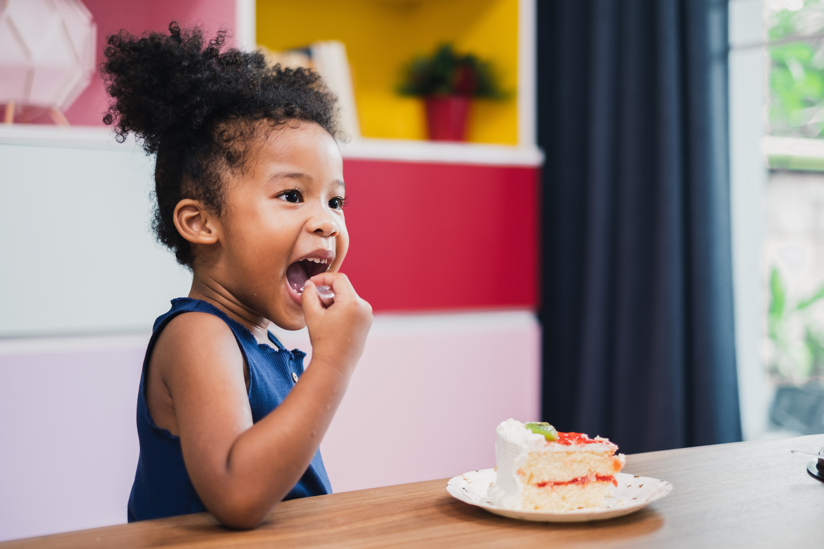 Criança comendo bolo.