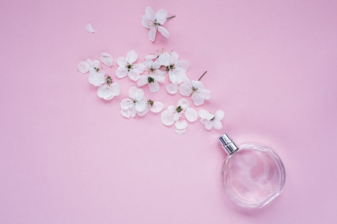 Vidro de perfume com flores em fundo rosa
