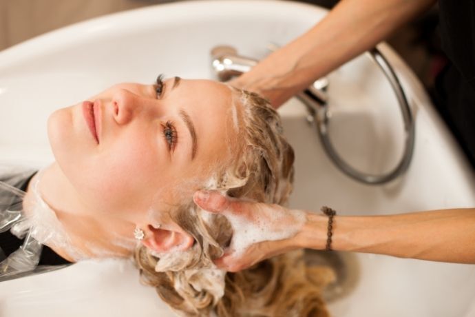 Mulher loira lavando o cabelo com shampoo