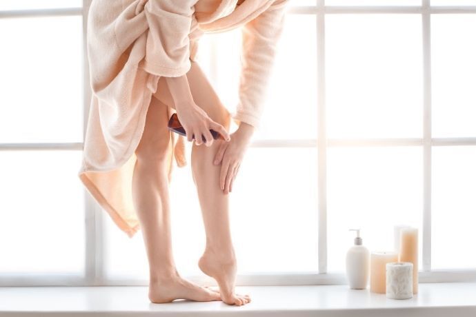Mulher passando óleo corporal nas pernas
