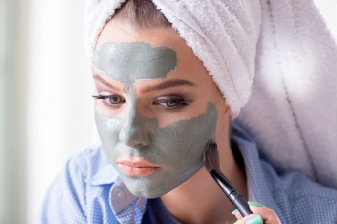 Mulher aplicando máscara facial verde com pincel